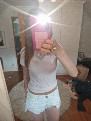 Rosa croppad t-shirt med spets - Rosa croppad t-shirt i bomull med v-ringning och snygg spetsdetalj vid halsen. Toppen har korta ärmar och sitter tight för en fräsch och enkel look! köpte från gina young men sydde den från en långärmad t kortärmad!!
