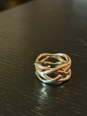 Flätad silverring i 925 sterling - Snygg och unik ring i 925 sterling silver med flätad design. Ringen har en bred form och flera band som korsar varandra, vilket ger ett trendigt och modernt intryck. Perfekt för dig som gillar statement-smycken och vill sticka ut lite extra.