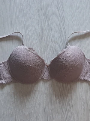 Ljusrosa spets-bh från Serenity - Säljer en ljusrosa bh från Serenity med vadderade kupor och vacker spetsdetalj över hela bh:n. Axelbanden är justerbara och bh:n har en klassisk bygelmodell. Perfekt för dig som gillar romantisk och feminin stil. Bh är aldrig använd.