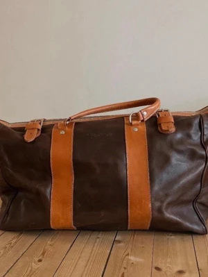 Nudie jeans keepall - Säljer en äldre nudie jeans keepall väska som är runt 10 år gammal. Väska görs inte längre vilket gör att den är rätt sällsynt. Väskan kostade 8000 ny. Några defekter är tydliga som att en av fötterna/plupp men inget som påverkar negativt. Små repor på lädret finns vilket är vanligt vid läder som används. Måtten är 49,5 cm lång, 20,5 cm bredd och 39 cm hög. En otrolig väska för dig som tänker resa!