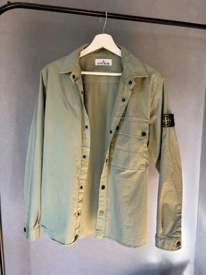 Ljusgrön overshirt från Stone Island - Stilren ljusgrön overshirt från Stone Island med klassisk krage, knappstängning och en stor bröstficka med knapp. 