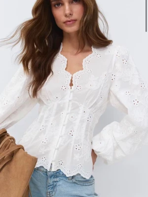 Vit broderad blus med puffärm - Prislappen på! Oanvänd, slut på hemsidan. Superfin vit blus från Monki med broderade blommor, puffiga långärmar och knappar framtill. Blusen har en söt vågig kant vid halsringningen och nederkanten. Tillverkad i bomull med romantisk känsla och figurnära passform.