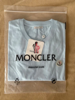 Ljusblå Moncler t-shirt - En helt ny Moncler t-shirt i färgen ljusblå Nyskick ligger på mellan 2200-2500