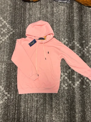 Rosa Ralph Lauren hoodie - Helt ny rosa polo ralph lauren hoodie i storlek S/XS, skit skön att ha på sig o jätte snygg, perfekt nu inför sommaren. Den är lite liten i storlek men kan passa ifall man har S då sitter den mer slim annars om man har XS så sitter den mer normalt👍🏼