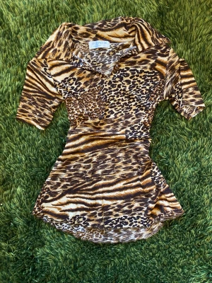 Leopardmönstrad mesh kortklänning Fenix - Letar hem till en kort klänning/längre topp i mesh från Fenix med leopard- och tigermönster i brunt, beige och svart. Klänningen har korta ärmar, krage och figurnära passform. Står L på lappen, men är snarare M eller S. Väldigt cool och unik!