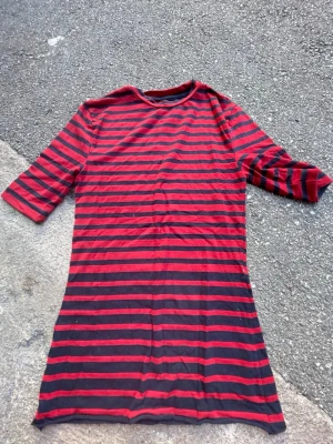 Randig röd och svart t-shirt Superdry - Säljer en randig t-shirt från Superdry i rött och svart. T-shirten har trekvartsärm och är tillverkad i mjuk bomull. Perfekt för dig som gillar en lite längre modell och vill sticka ut med klassiska färger och mönster.