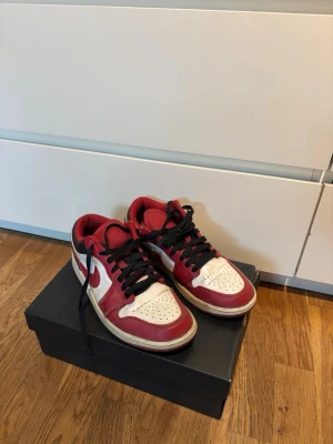 Nike Air Jordan 1 Low  - Säljer ett par Nike Air Jordan 1 Low sneakers i rött, vitt och svart läder. Storlek 41, låda ingår. Köpta 2022 när de var splitternya hos Nike.
