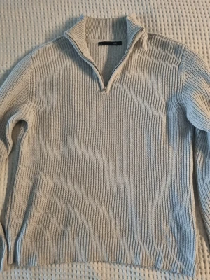Beige stickad tröja med halvzip - Stickad tröja i beige från 157 med halvzip och hög krage. Tröjan har ribbstickat material och långa ärmar, perfekt för lager-på-lager och chill dagar. Enkel och stilren design som funkar till jeans eller joggers.