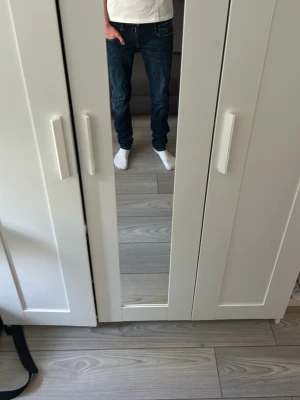 Mörkblå jeans från replay - Säljer ett par mörkblå jeans från Replay  med klassisk femficksmodell och kontrastsömmar. Jeansen har smal passform och detaljerade bakfickor med Replays signatursöm. Perfekta för en avslappnad och stilren look.