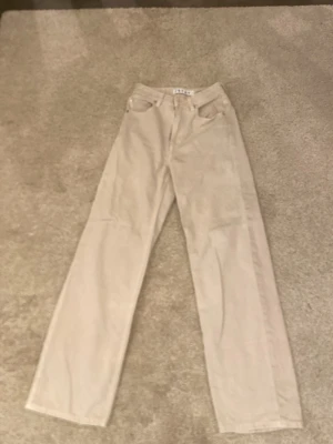 Beige raka jeans från STAY - Säljer ett par beige jeans från STAY med rak passform och klassisk femficksdesign. Jeansen har bälteshällor, knappgylf och är tillverkade i ett mjukt bomullsmaterial. Perfekta för en clean och avslappnad stil.