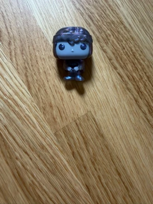 Funko Pop, Dustin from the Upside down. Stranger things - Säljer en Funko Pop vinylfigur med stor huvud och hjälm. Figuren har mörkt hår, stora svarta ögon och bär en mörk outfit med detaljer i silver och blått. Perfekt för samlare eller som dekoration.