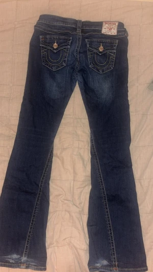 Mörkblå bootcut jeans True Religion - Säljer dessa för att dom är för stora, dom har lite fläckar på ena låret och lite söndriga där nere. lappen av storleken är avklippt men det är w28.