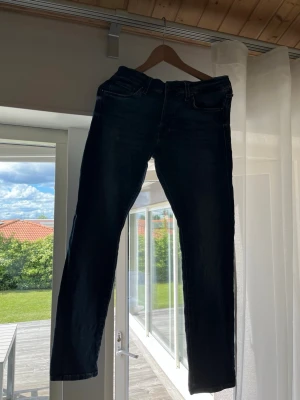Mörkblå slim fit jeans - Säljer ett par mörkblå slim fit jeans med klassisk femficksdesign och dragkedja. Jeansen har en snygg tvättad look och är tillverkade i mjukt denimtyg som sitter skönt. Perfekta för dig som gillar en enkel men stilren stil. Storlek 29/30