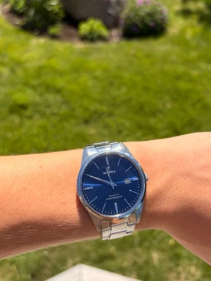 Blå Festina klocka med metallarmband - Stilren klocka från Festina med blå urtavla och datumvisnining. Använd i ish 5 månader, bra skick. Om klockan är för liten finns det delar att sätta dit för att den ska bli större!😁