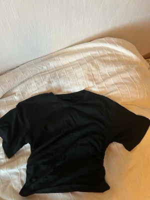 Svart basic t-shirt i bomull - En enkel svart t-shirt i mjuk bomull. Klassisk passform med rund hals och korta ärmar. Perfekt att matcha med jeans eller shorts för en clean och stilren look.