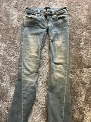 True Religion Joey Low Rise Flare Jeans - Säljer ett par ljusblå True Religion Joey jeans med låg midja och utsvängda ben. Har sytt om dom i midjan så dom är JÄTTE LÅGMIDJADE 