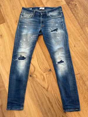 Jack & Jones jeans LIMITED EDITION  - Säljer ett par blåa jack & Jones jeans med slitningar. normalt stretchigt denim. Perfekt för dig som gillar en trendig och avslappnad stil. (31/32 storlek)