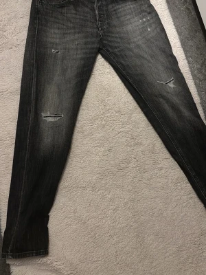 Jack and Jones - Snygga svarta jeans med slitningar på låren och knäna. Jeansen har raka ben och en klassisk femficksmodell. Materialet är denim med en tvättad look som ger en cool och avslappnad stil.