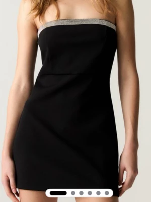 Slutsåld coctail klänning med diamanter  - Svart axelbandslös kort klänning med diamanter upptill. Klänningen har en figurnära passform och dragkedja bak. 💎 En diamant har lossnat fram men inget man tänker på🥰 