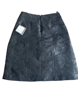 Svart kjol med diskret mönster Habsburg - Elegant svart kjol från Habsburg i modell Margareta. Kjolen har ett diskret, ton-i-ton mönster och en klassisk rak form som slutar ovanför knäet. Perfekt för dig som gillar stilrena och exklusiva plagg med en lyxig känsla.