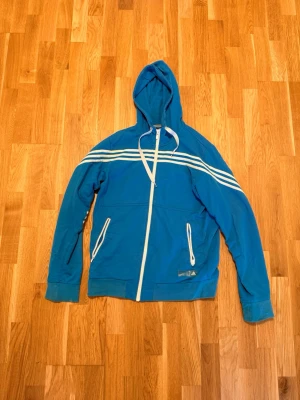 Adidas zipper Hoodie  - Jag säljer en blå zipperhoodie från Adidas! Väldigt bra skick och kvalité och ser riktigt bra ut! Storlek L, säljer denna för 300kr! Skriv vid funderingar:)