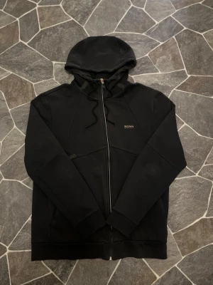 Hugo Boss Zip - En mycket fin zip ifrån Hugo Boss. Tröjan har inga defekter därmed är i fint skick. Säljs pga ingen användning men sitter fint i storlek.   Priset kan diskuteras!