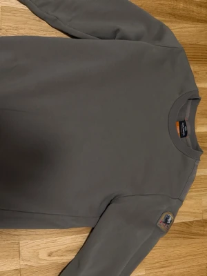 Mörk grön tröja från parajumper   - Snygg grön sweatshirt ish från P.J.S med rund halsringning. Tröjan har en klassisk passform och är tillverkad i mjukt bomullsmaterial. Perfekt för en avslappnad och stilren look. Passar både M och S