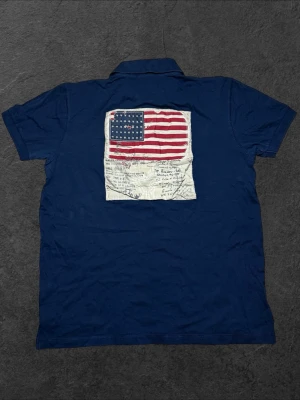 Vintage Ralph Lauren USA pikétröja- herr strl L (S) - Säljer en marinblå Polo Ralph Lauren pikétröja i storlek L (motsvarar S) med broderad USA-flagga på ryggen och broderad Ralph Lauren-sköld på bröstet  👕 Märke: Polo Ralph Lauren 📏 Storlek: L (passar som S) 🎨 Färg: Marinblå 🧵 Material: 100% bomull, tillverkad i USA 📐 Mått: Längd 61 cm, bredd 49 cm 📍 Skick: Mycket bra skick (se bilder)  💬 Har du några frågor är det bara att höra av dig! 💰 Vid snabb affär kan priset diskuteras. 📦 Skickar alltid inom 24 timmar!
