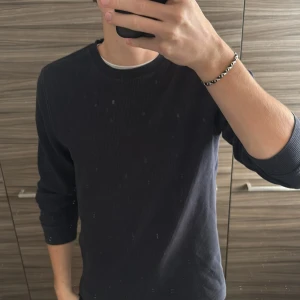 Blå ribbad långärmad tröja - En stilren blå långärmad tröja med ribbad struktur och rund halsringning. Tröjan har en smal passform och är perfekt för en avslappnad och trendig look. Enkel att matcha med olika outfits.