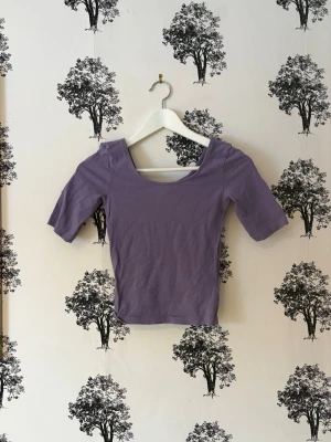 Ljuslila croppad topp - Snygg ljuslila croppad topp med bred urringning och halvlånga ärmar. Perfekt till jeans eller kjol för en trendig look. Mjuk och stretchig känsla, passar dig som gillar enkel men stilren design.