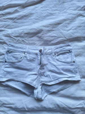 Vita shorts från HM Divided - Snygga vita jeansshorts från H&M med klassisk femficksdesign och knappgylf. Modellen är kort och har en mid/lowwaist passform. Perfekta till sommaren🌟☀️