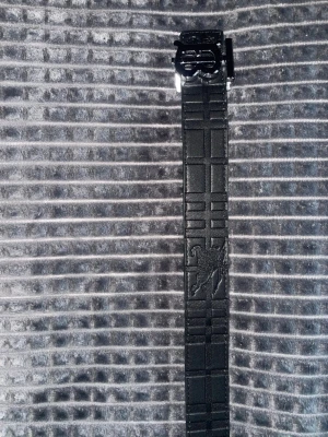 Burberry-bälte - Snyggt vändbart bälte från Burberry med klassiskt rutigt mönster på ena sidan i beige, rött och svart samt helsvart sida med präglad logga och metallspänne. Perfekt accessoar för att lyfta din outfit med en lyxig touch.