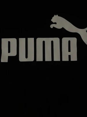 Svart Puma t-shirt med logga - Snygg svart t-shirt från Puma med stor vit logga och text framtill. Klassisk passform och korta ärmar, perfekt för en sportig och avslappnad stil. Tillverkad i mjuk bomull som känns skön mot huden.