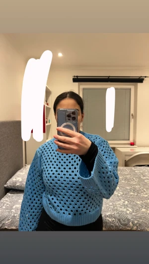 Blå stickad tröja med hålmönster - Snygg blå stickad tröja med hålmönster och breda ärmar. Tröjan har en avslappnad passform och ribbstickade muddar vid ärmslut och midja. Perfekt för lager-på-lager och ger en trendig look.