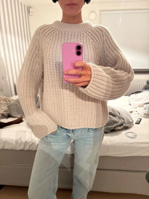 Beige chunky stickad tröja - Säljer en beige chunky stickad tröja med grov ribbstickning och rund hals. Tröjan har långa ärmar och en avslappnad passform, perfekt för lager-på-lager. Materialet känns mjukt och mysigt, perfekt för kyliga dagar.