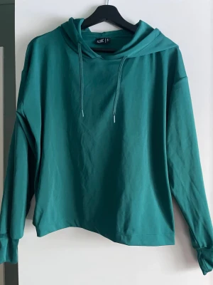 Grön hoodie från Iconic - Snygg grön hoodie från Iconic med avslappnad passform och långa ärmar. Tröjan har huva med dragsko. Perfekt för träning eller chill dagar.