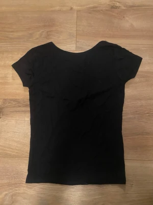Svart basic t-shirt utan rygg - En enkel svart t-shirt utan rygg och korta ärmar. Modellen är figurnära och passar perfekt till alla typer av outfits. Tillverkad i mjukt bomullsmaterial för skön känsla hela dagen. Från lager 157 i storlek XS💗