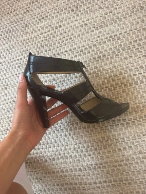 Svarta michael kors klackade sandaler med dragkedja - Säljer ett par svarta michael kors sandaler med hög klack och öppen tå. 
