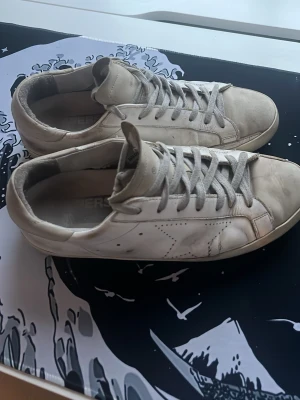 Golden goose sneakers - Snygga vita sneakers med lågt skaft och klassisk siluett. Skorna har vita snören, perforerade detaljer på sidan och en svart sula undertill. Tillverkade i läder för en clean look som passar till det mesta.