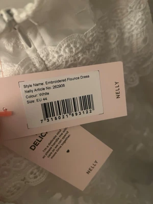 Vit broderad klänning från Nelly - Säljer en vit broderad klänning från Nelly i storlek 44. Klänningen har fina spetsdetaljer och volanger som ger en romantisk känsla. Perfekt för dig som vill ha en feminin look med extra detaljer.