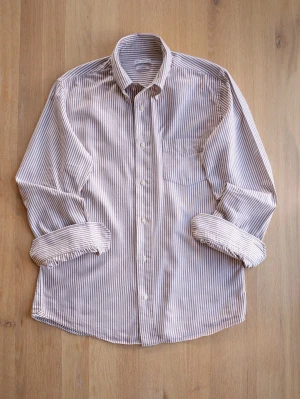 Brun och vit randig flanellskjorta från Gutteridge - Säljer en brun och vit randig skjorta från Gutteridge i mjuk flanell. Skjortan har klassisk krage, knäppning framtill och en bröstficka. Perfekt för dig som gillar en avslappnad men ändå stilren look. Storlek 41, men sitter som M