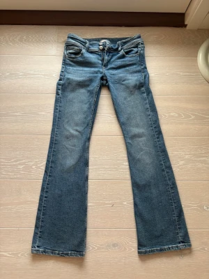 Blå bootcut jeans med dubbla knappar - Säljer ett par blå bootcut jeans med dubbla knappar i midjan från Gina tricot. De är andvända ca 10-15 gånger och sitter väldigt fint på. (Pris kan diskuteras)