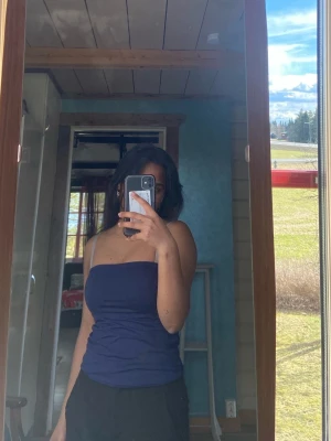 Mörkblå bandeau tubtopp - Säljer en mörkblå bandeau tubtopp med enkel och stilren design. Toppen är axelbandslös och sitter tight mot kroppen, perfekt för varma dagar eller som layering-piece. Materialet känns mjukt och stretchigt.