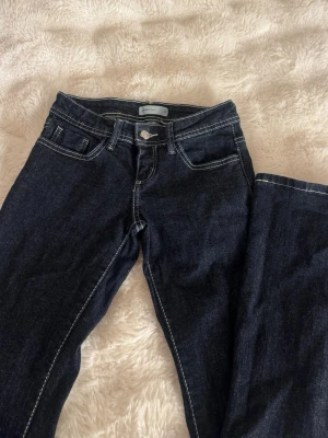 Gina trixig ultra low jeans - Snygga mörkblå jeans med utsvängda ben och tydliga vita sömmar. De är low waist och nästan helt oanvända. 