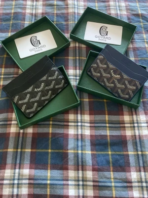 Korthållar bundle. - Två stilrena korthållare i svart och marinblått. Båda har det klassiska mönstret i vitt samt flera fack för kort. Tillverkade i canvas med läderdetaljer. Perfekt för dig som vill ha en lyxig och smidig plånbok i fickan.