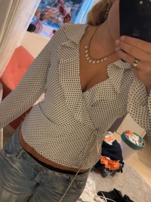 Vit omlottblus med svarta prickar - Super fin blus som jag tyvärr nu ska sälja! Jag köpte blusen på en secondhand och förstår inte riktigt hur den ska knytas så jag improviserade lite😅🥰❤️