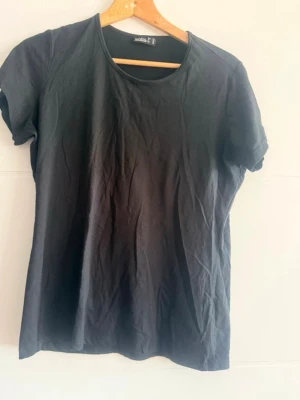 Svart basic t-shirt från Janina - En enkel svart t-shirt från Jack & Jones med rund hals och korta ärmar. Tillverkad i mjuk bomull som känns skön mot huden. Perfekt att matcha med jeans eller shorts för en clean och avslappnad stil.