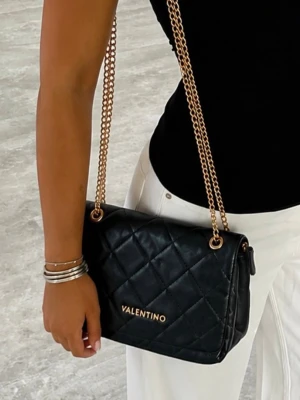 Svart quiltad handväska Valentino - Snygg svart quiltad handväska från Valentino med guldfärgade kedjehandtag och logga framtill. Väskan har en klassisk rektangulär form och elegant design som passar till många olika outfits. Materialet ser ut att vara konstläder med mjuk struktur.har tappat lite färg på vissa platser men syns inte så mycket 
