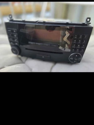 Mercedes benz w203 stereo - Säljer en svart multimediaenhet till bil med stor display, knappsats på båda sidor och flera reglage. Enheten har CD-spelare och olika anslutningar på baksidan, inklusive fläkt och videoport. Perfekt för dig som vill uppgradera bilens elektronik.