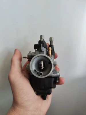 Förgasare dellorto 16mm phgb  - Säljer en förgasare i metall och svart plast, perfekt för dig som behöver reservdel till moped eller motorcykel. Kompakt design med flera anslutningar och justerskruvar. Passar till olika modeller och är enkel att montera.